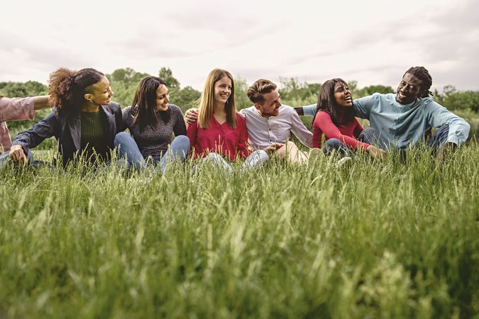 Multiethnic university students having fun hugging resting on the grass smiling and having fun together