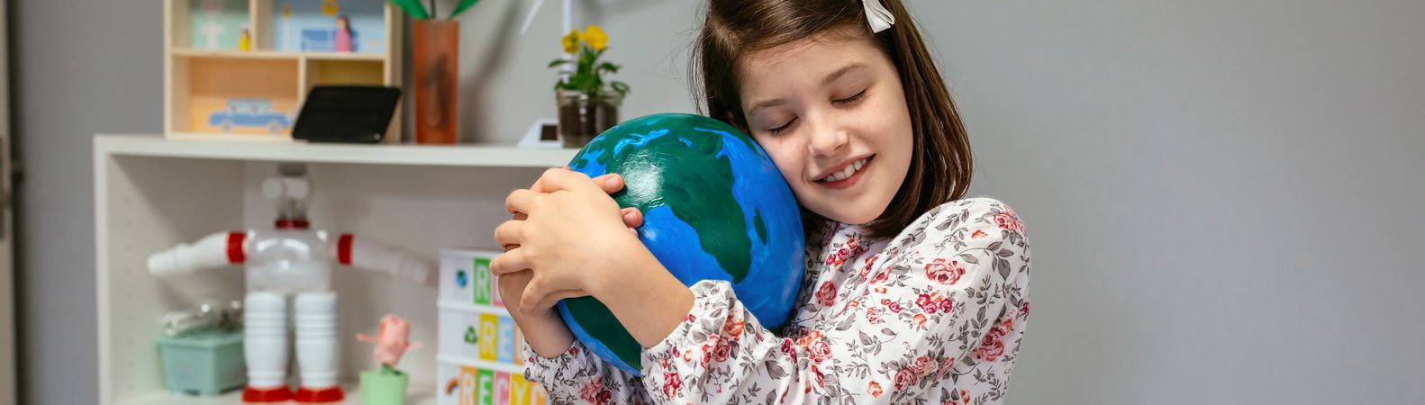 Female student hugging a handmade globe world at ecology classroom