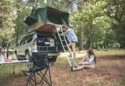 Woman climbing ladder to tent over car