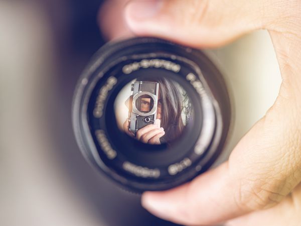 Lens with reflection of woman with analog photo camera