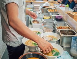 Young male cook serving bowls with ramen