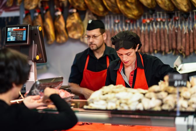 Man and woman in butcher shop serving a customer
