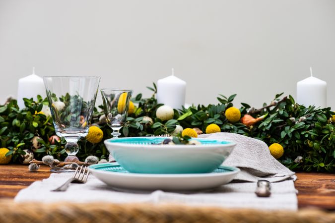 Side view of Easter table setting with decorative eggs in foliage