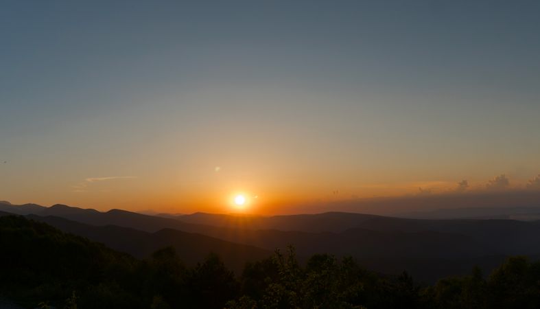 Sunset over distant hills with clear sky.