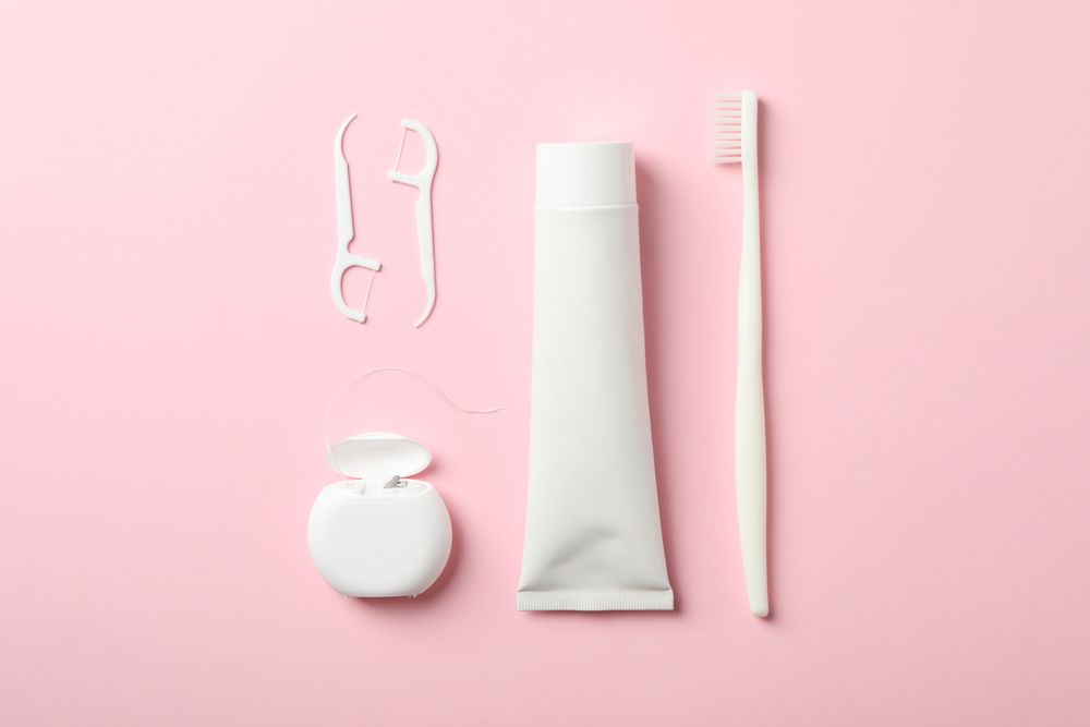 Tools for dental care on pink background, top view