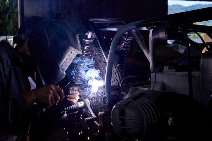 Male mechanic welding motorcycle parts