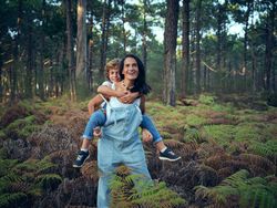 Son riding back of mother while walking in nature