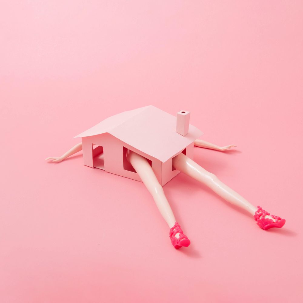 Pink house with oversized doll limbs coming out of the windows