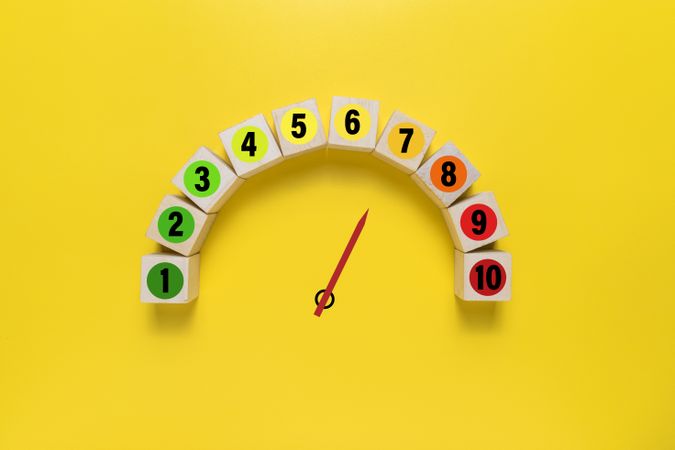 risk level meter indicator from low to high with 1 to 10 scale numbers on wooden blocks isolated on yellow background. concept of risk management