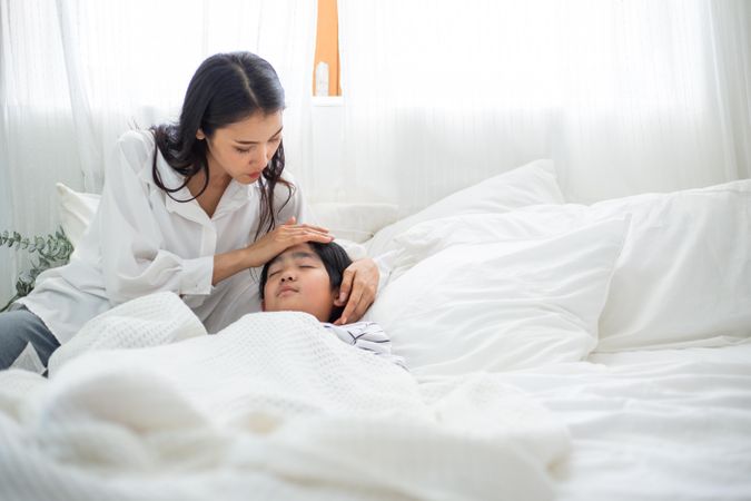 Woman comforting male child as he goes to sleep