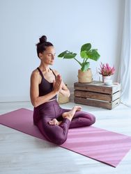 Woman sitting on mat and meditating in Padmasana pose
