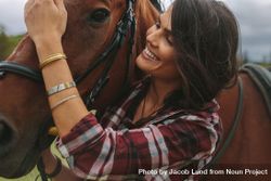 Close up of woman petting the nose of her horse and smiling 4NQmD5