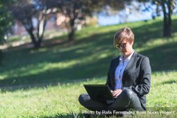 Woman sitting cross legged in park with laptop 5zgDg4