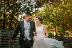Happy just married couple running along fence in garden