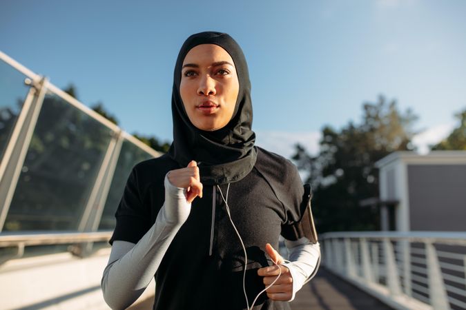 Sporty woman wearing hijab jogging outdoors in the city