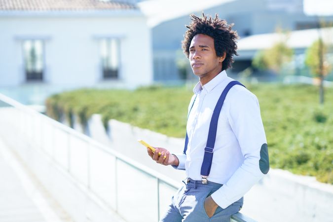 Man looking in the distance while waiting with phone in his hand