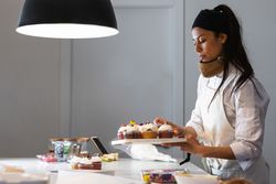 Female cook with cupcakes in kitchen