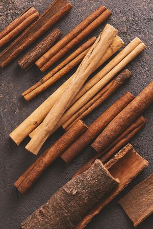 Different sizes of cinnamon sticks on brown background