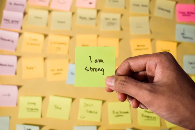 Hand hold sticky notes with words I am strong, Motivational personal development, inspirational handwriting