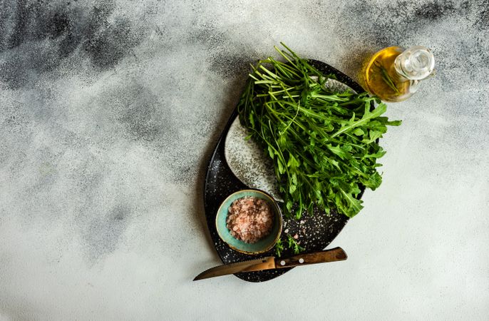 Looking down at healthy plate with bunch of arugula leaves and olive oil