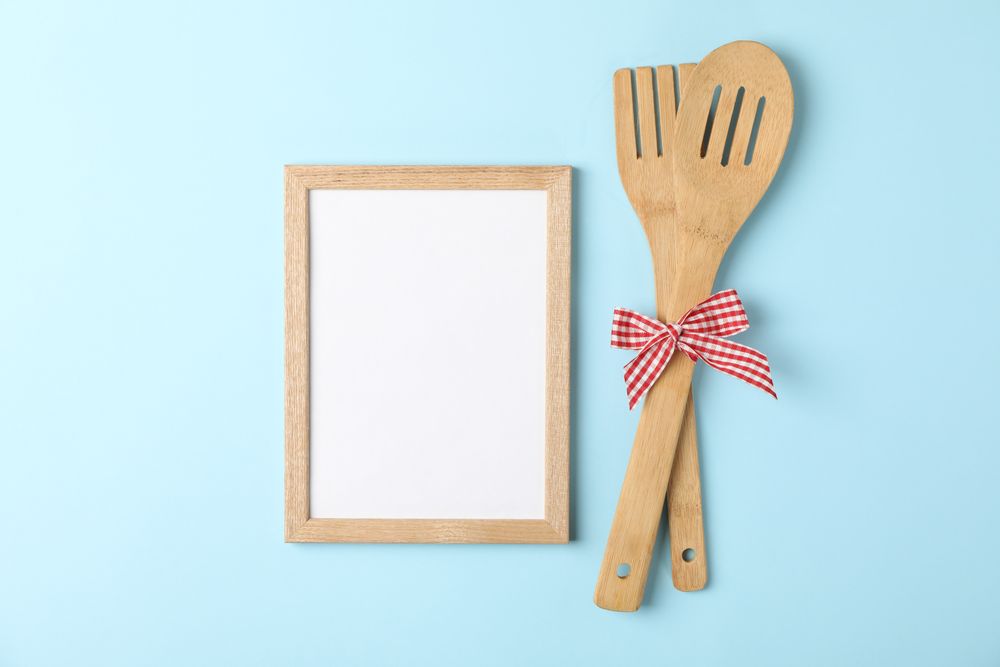 Wooden fork, kitchen spatula and blank space for text on blue background