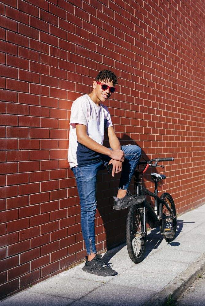 Young happy Black male leaning on wall