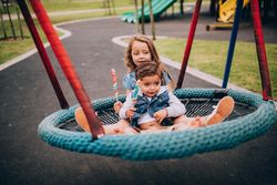 Two kids playing on a swing at a playground