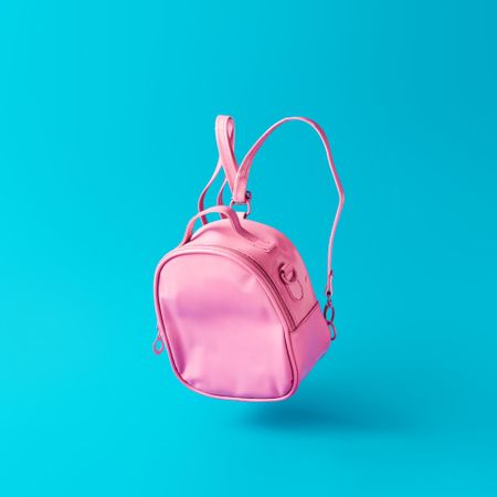 Pastel pink school bag floating on blue background