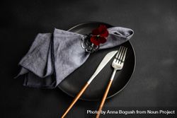 Top view of dark plate with cutlery and red flower 4Z8mW0