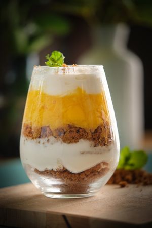 Glass of delicious cheesecake on table
