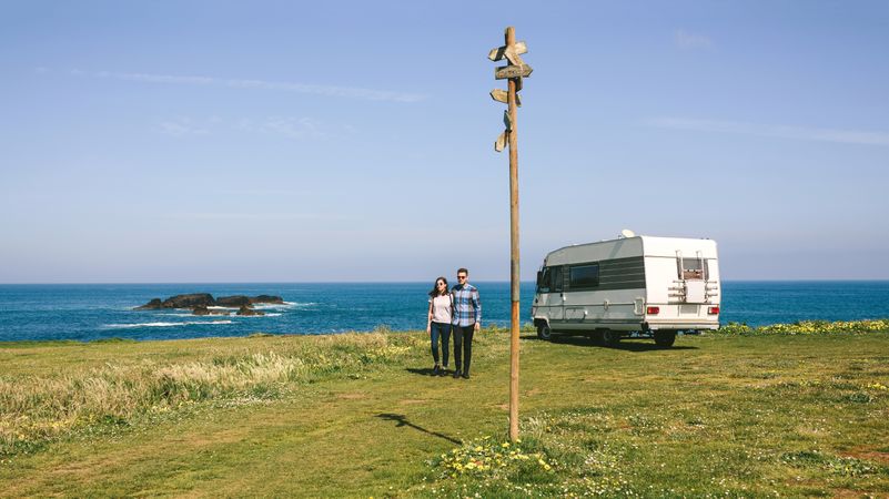 Couple taking a walk near the coast with a camper