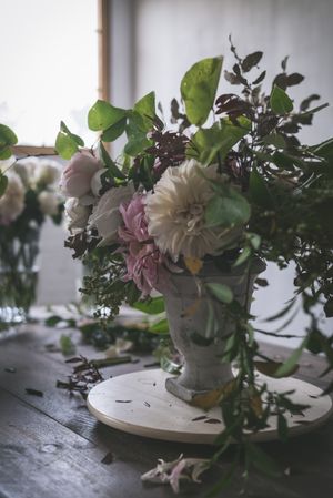 Composition of flowers and plants in vintage vase on board