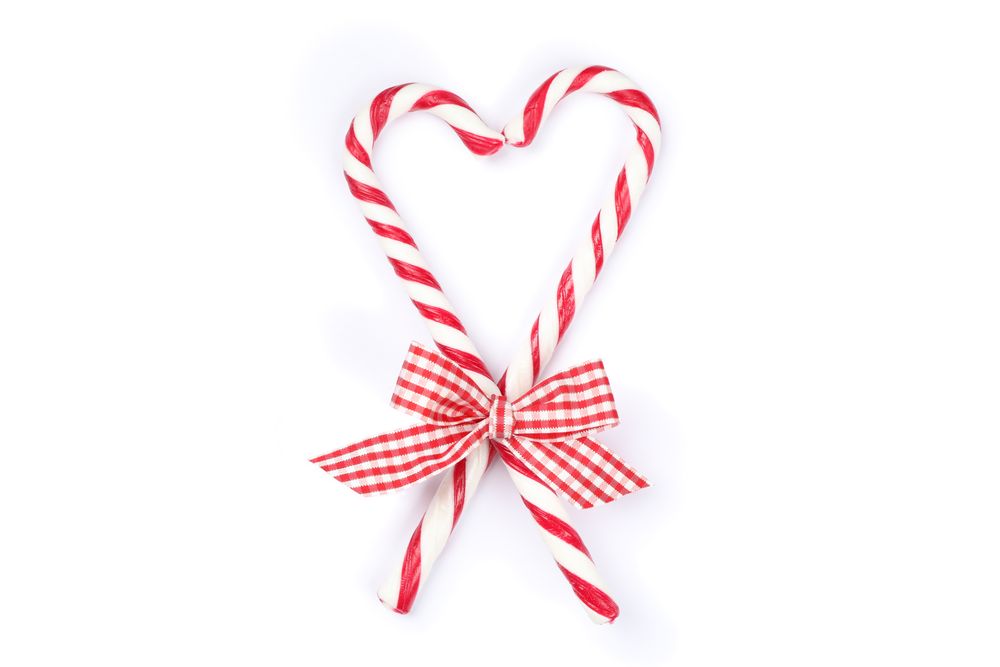 Sweet candy canes with bow isolated on plain background