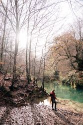 Anonymous woman standing near calm pond in autumn day