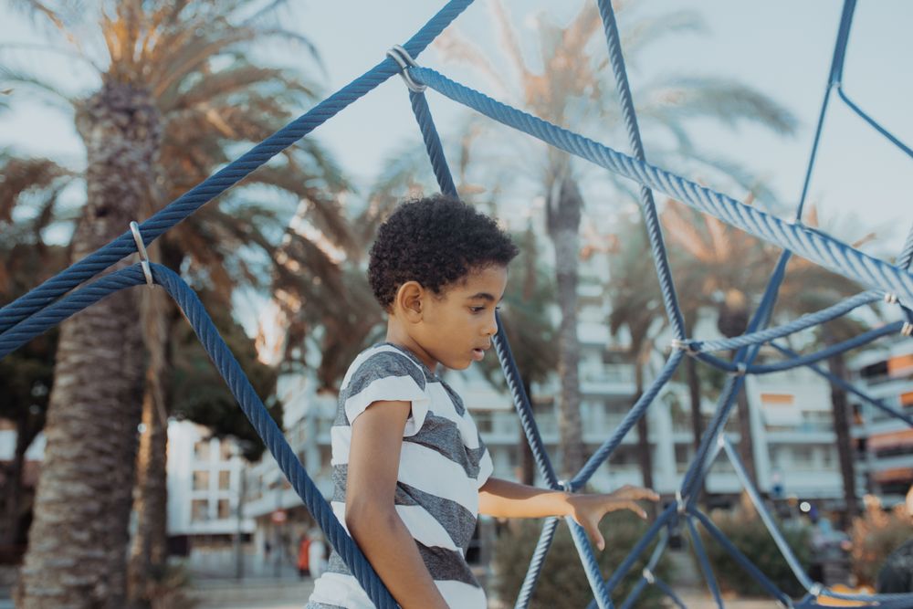 Funny Black boy on net on playground