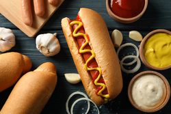 Tasty hot dog and ingredients on wooden background