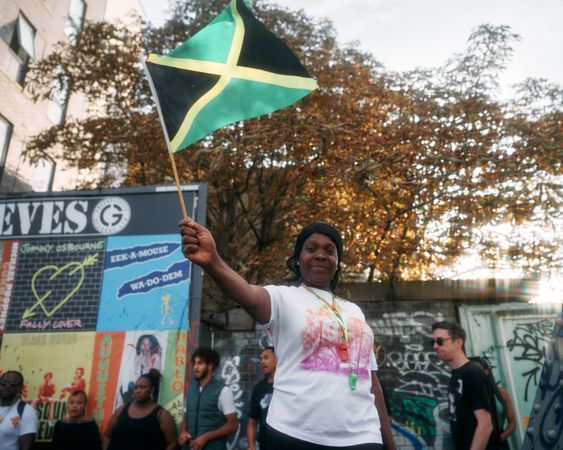 London, England, United Kingdom - August 27, 2022: Woman waving Jamaican flag in London street