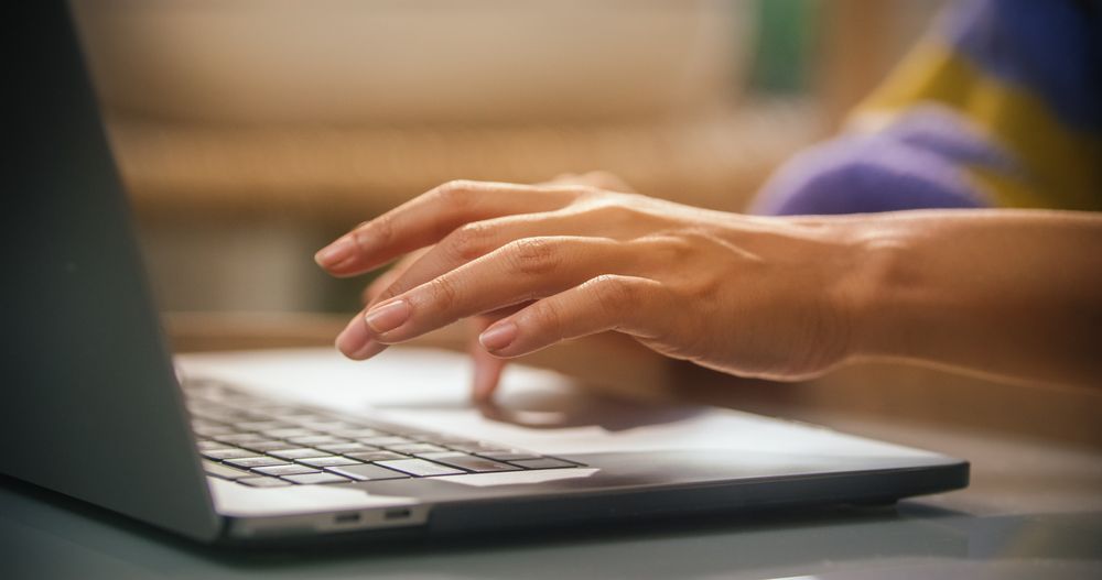 Close Up on Female Hands Typing and Using Laptop Computer in Sunny Cozy Apartment.