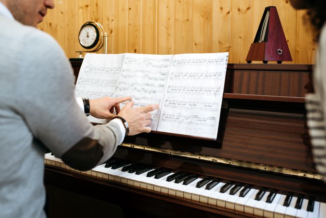 Man playing piano near woman teaching in studio