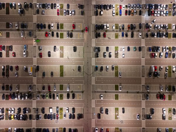 Aerial view of numerous cars of varying colors shapes and sizes neatly parked