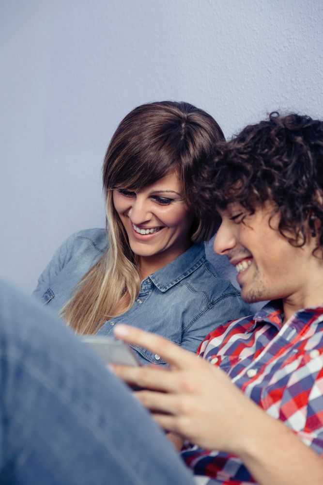 Cute couple in love looking smartphones and laughing