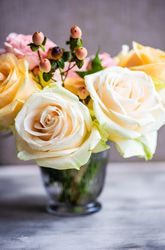Floral card with yellow flowers in glass on concrete background