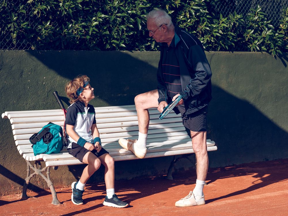 Male trainer teaching boy playing tennis