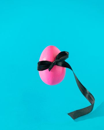 Pink egg on blue background with ribbon