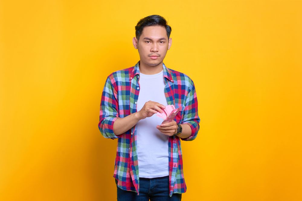 Serious Asian man holding cash in studio shoot