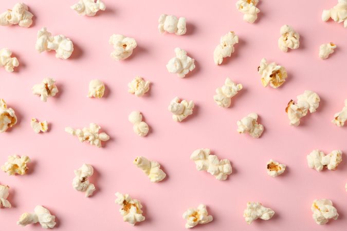 Flat lay composition with popcorn on pink background, closeup