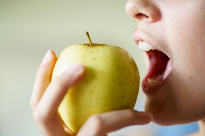Side view of girl about to bite into apple