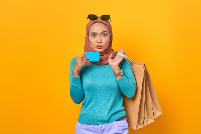 Surprised Muslim woman smiling with shopping bags and credit card