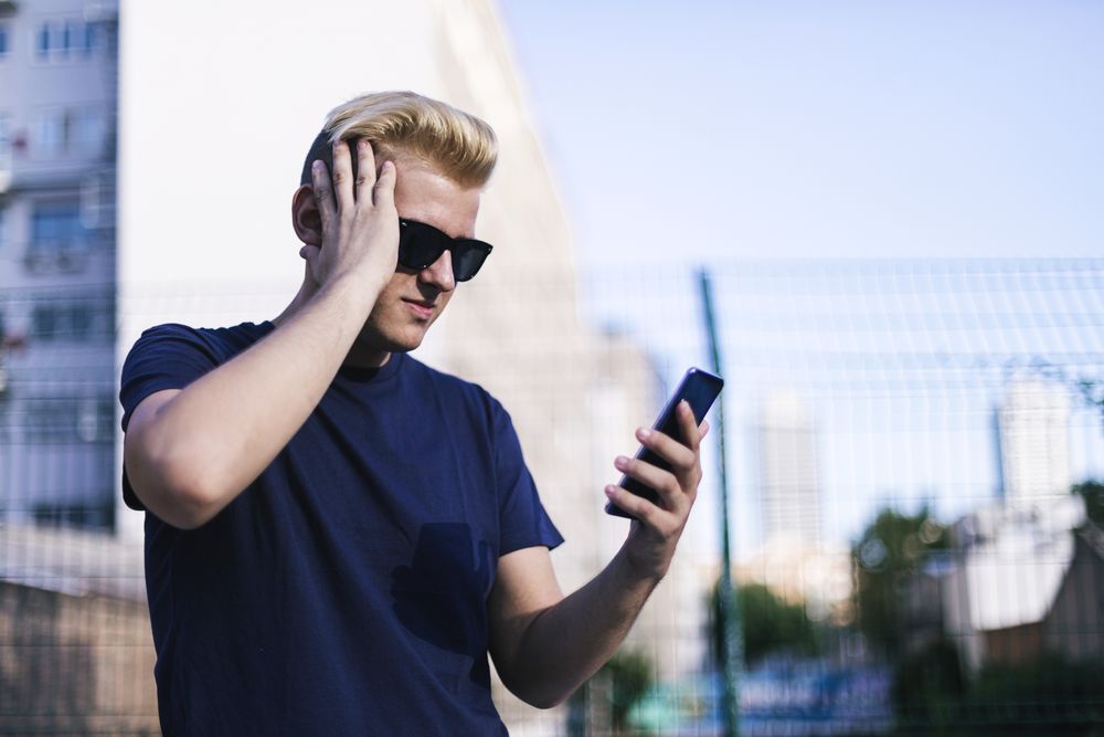 Young blond male using a cell phone on the street