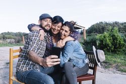 A group of friends sitting outdoors while taking a selfie